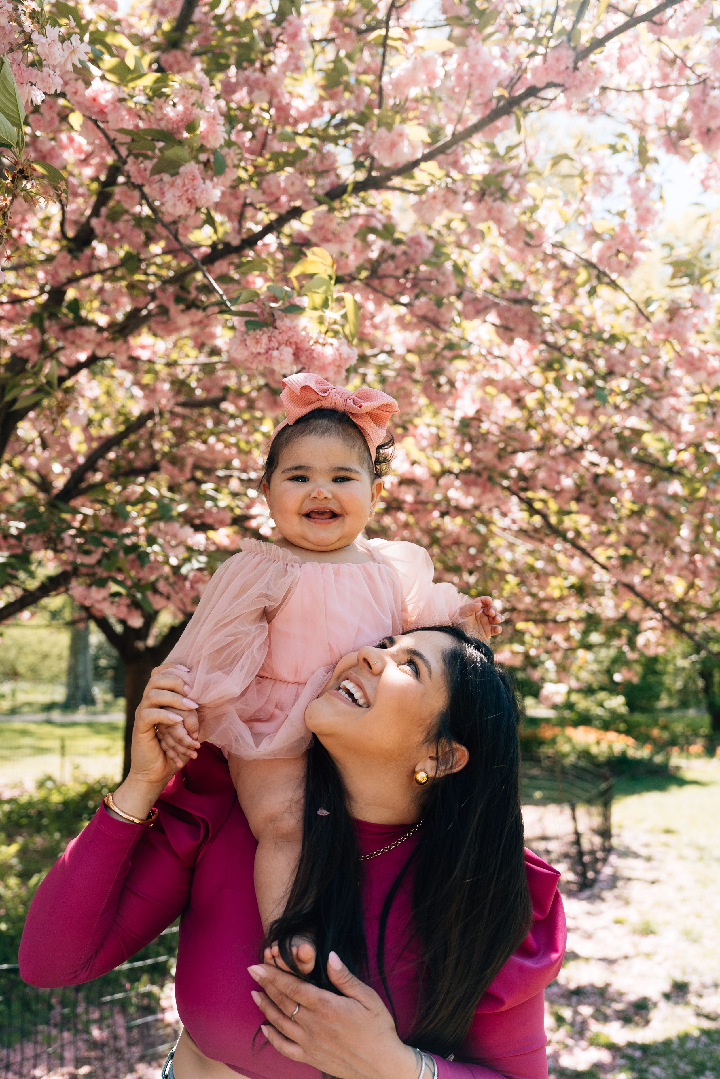 A joyful moment under blooming pink cherry blossom trees on a sunny spring day.