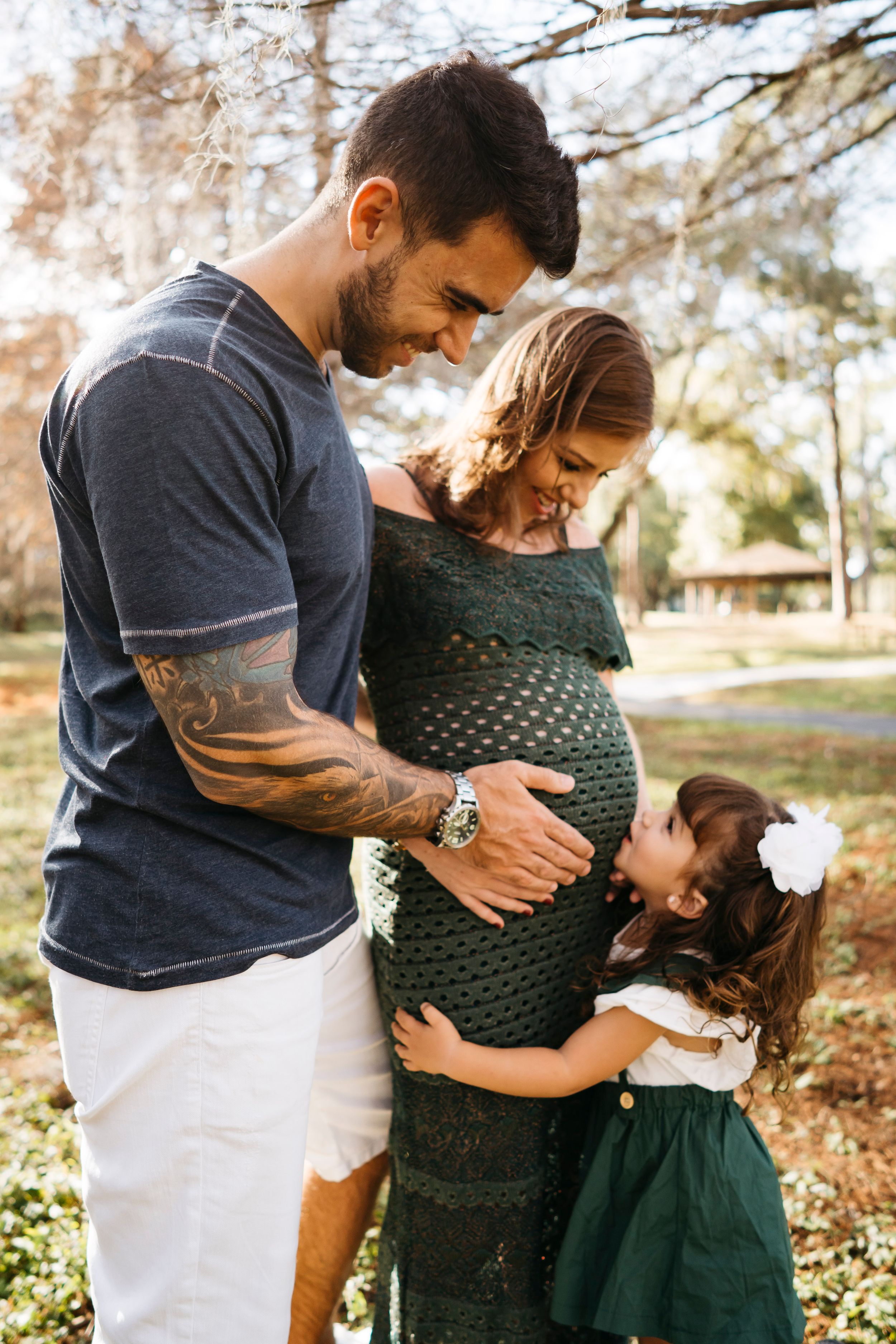 A couple embraces outdoors in autumn, with person wearing a green top and dark skirt as they share tender moments together.