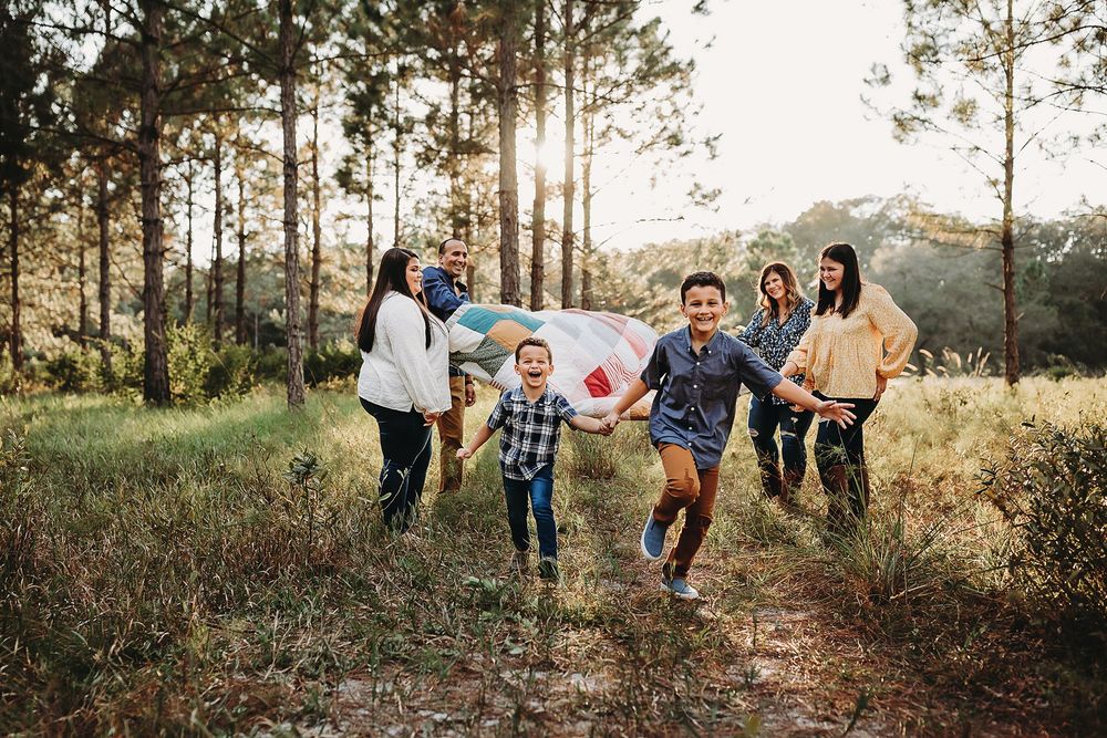 Group of people walking along a scenic forest path during golden hour sunset with sunlight filtering through trees.