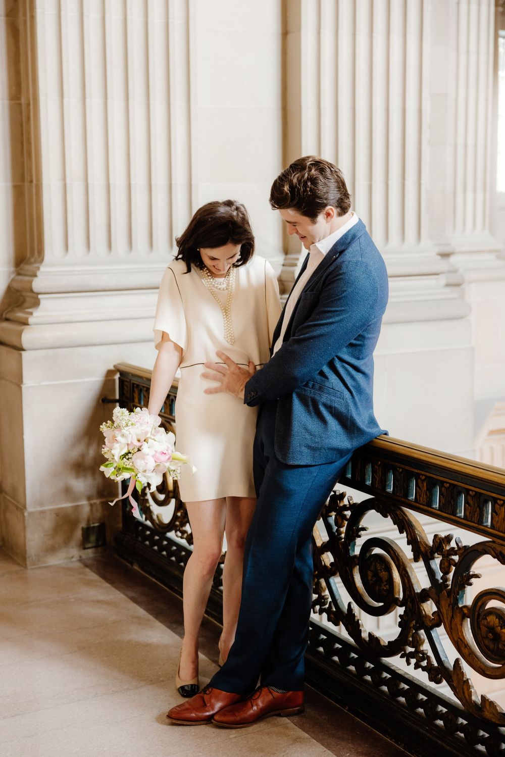 Couple shares intimate moment on vintage bench inside grand historic building.
