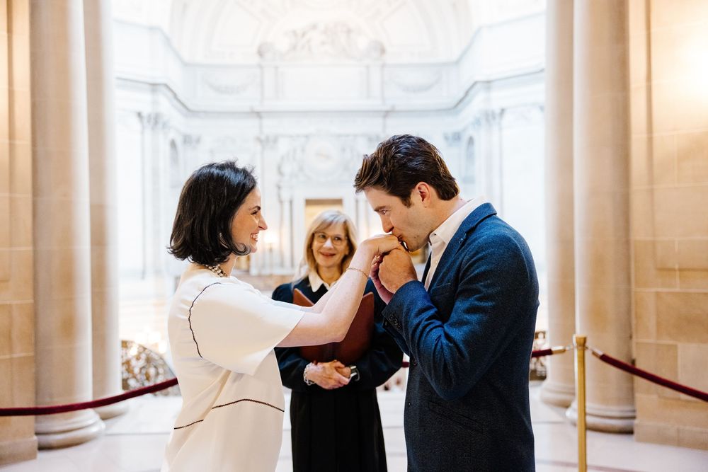 A romantic moment captured in a grand marble corridor with ornate wall sconces and elegant architectural details.