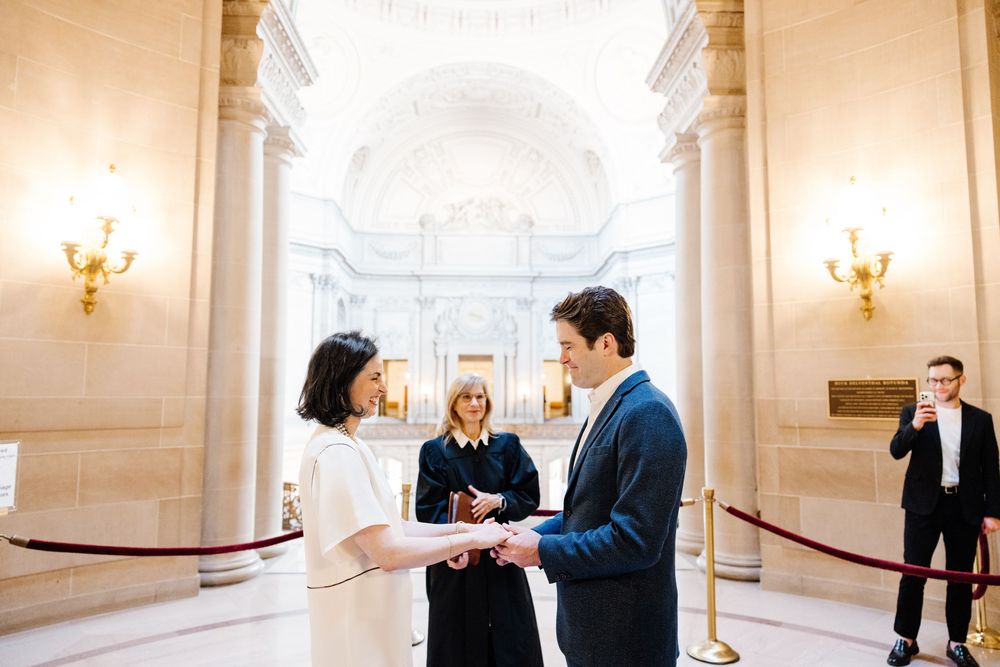 Elegant couple sharing tender moments in a bright indoor venue with ornate wall sconces and white columns.