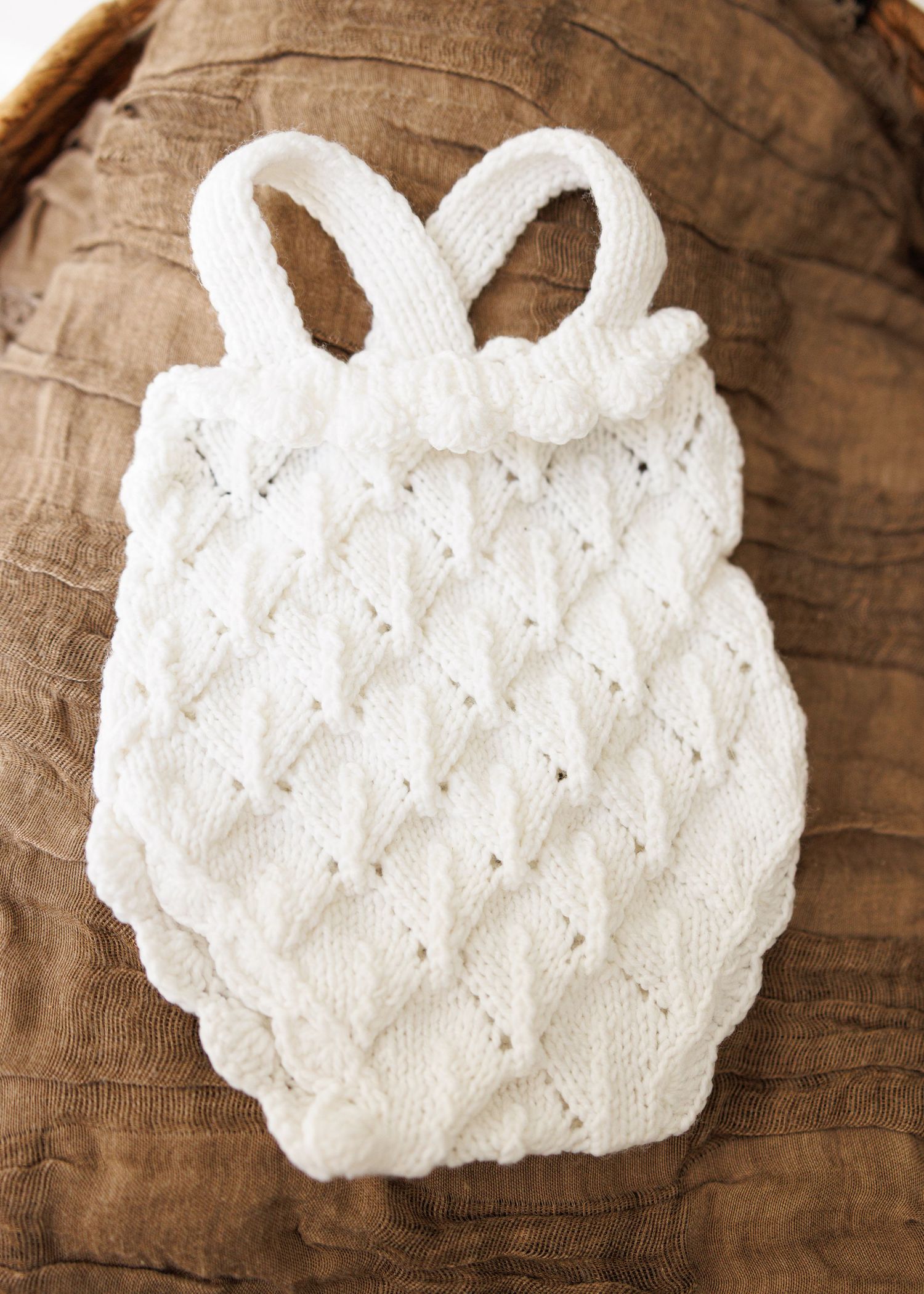 A small white teddy bear rests next to a business card on delicate lace fabric.