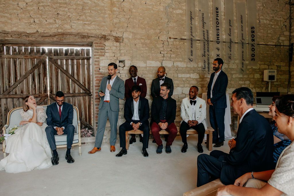 Wedding guests gathered around bride and groom during intimate rustic barn ceremony celebration.