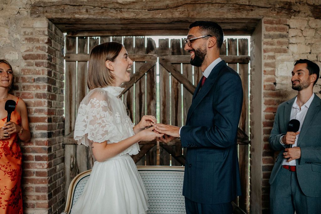 Bride and groom exchanging rings during intimate wedding ceremony in a rustic brick venue.