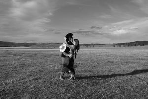 A black and white photo of a couple embracing in a vast open field.