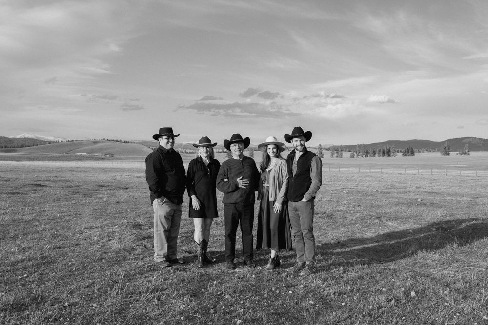 A black and white group photo of people in western wear standing in an open field.
