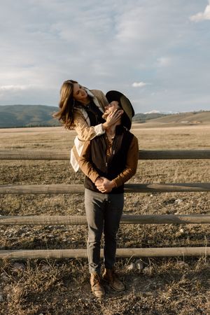 A romantic moment shared on a wooden fence overlooking vast open plains at dusk.