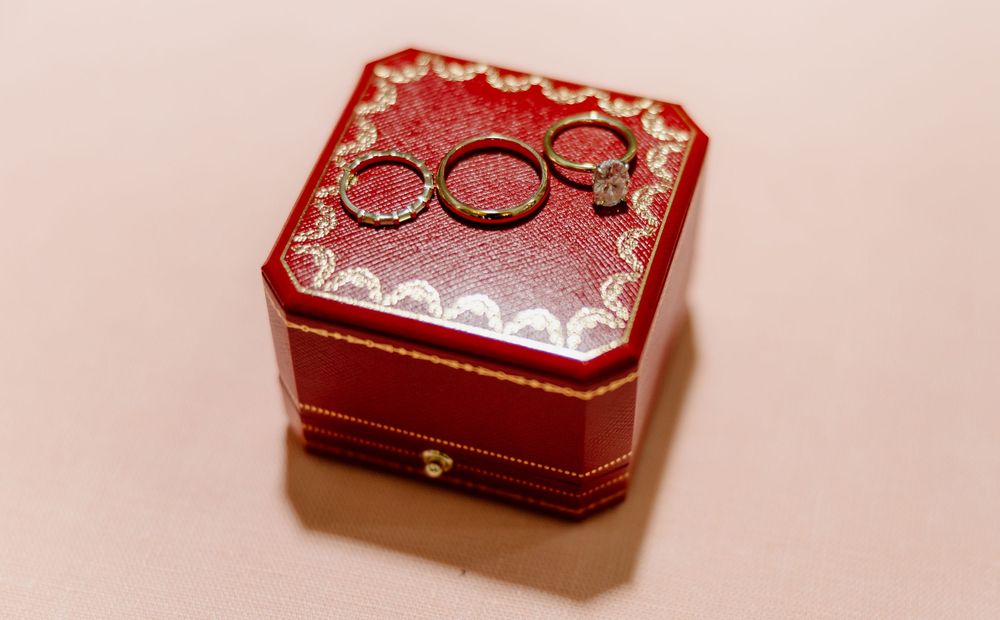 Red velvet ring boxes with wedding bands photographed on pink background.