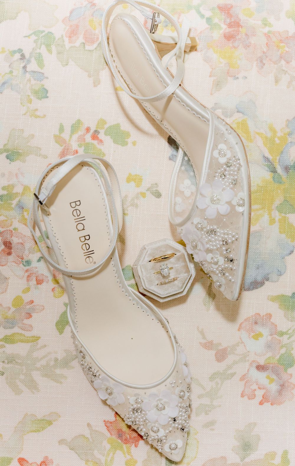 Elegant bridal shoes with crystal embellishments displayed on a delicate floral background.