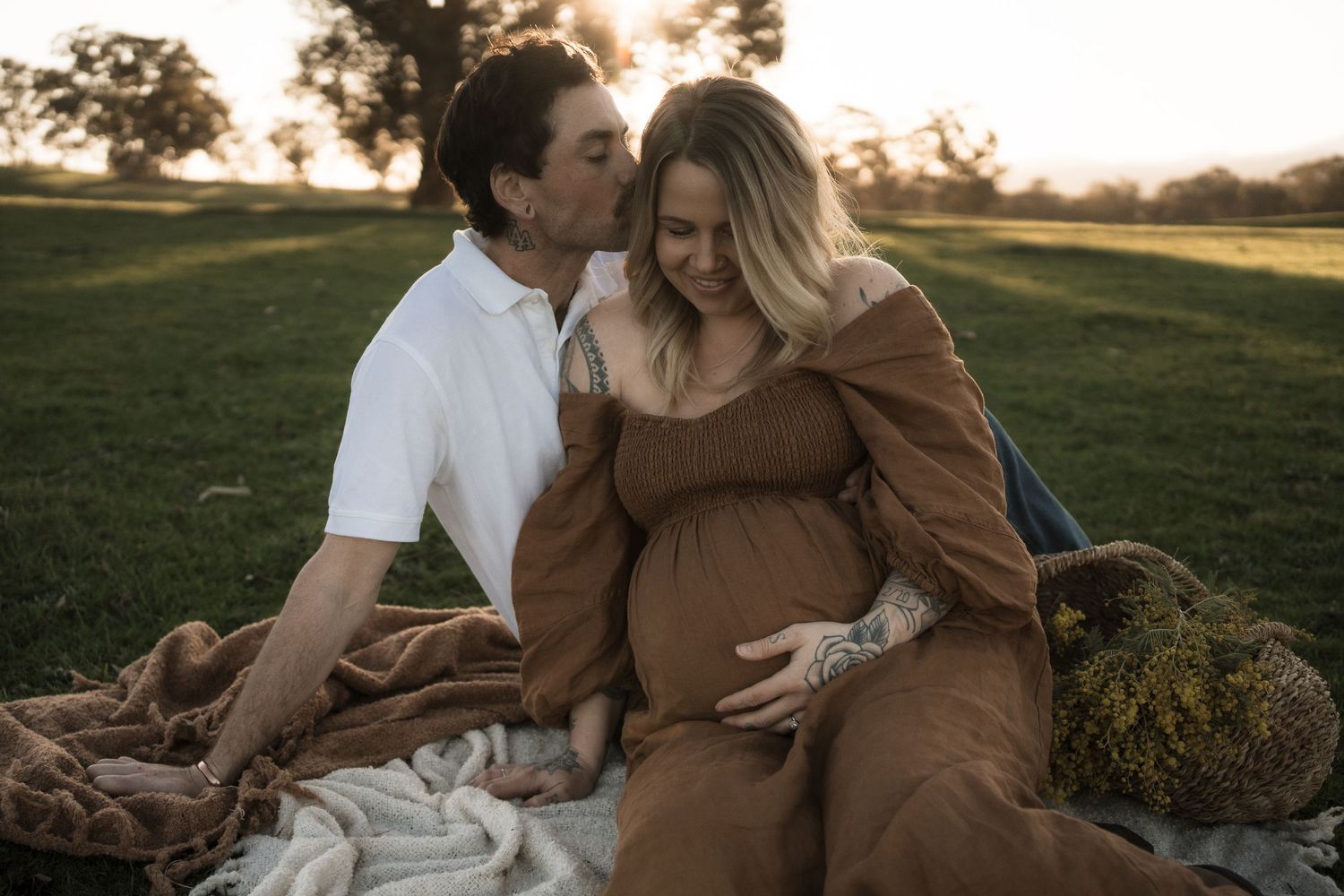 A couple embraces in a golden sunset field during a romantic maternity photoshoot in Mansfield