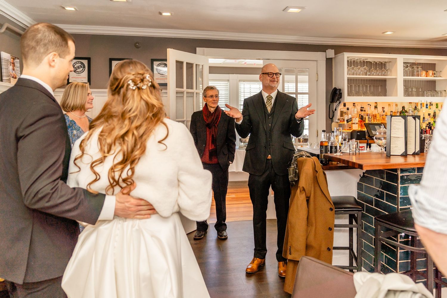 People gather in a modern bar area with warm lighting and elegant decor during what appears to be a special event.