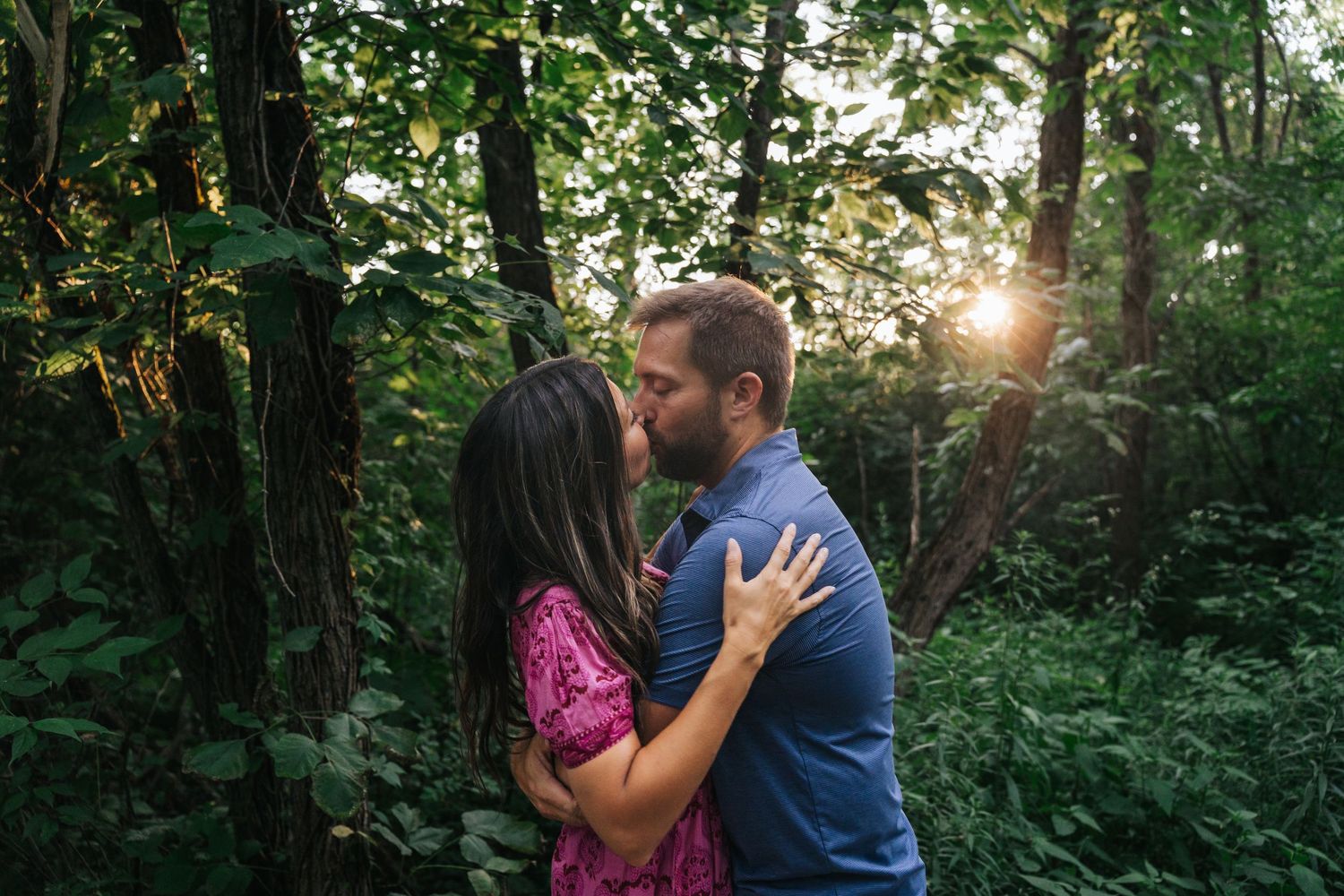 Romantic forest engagement session with sunlight streaming through trees.