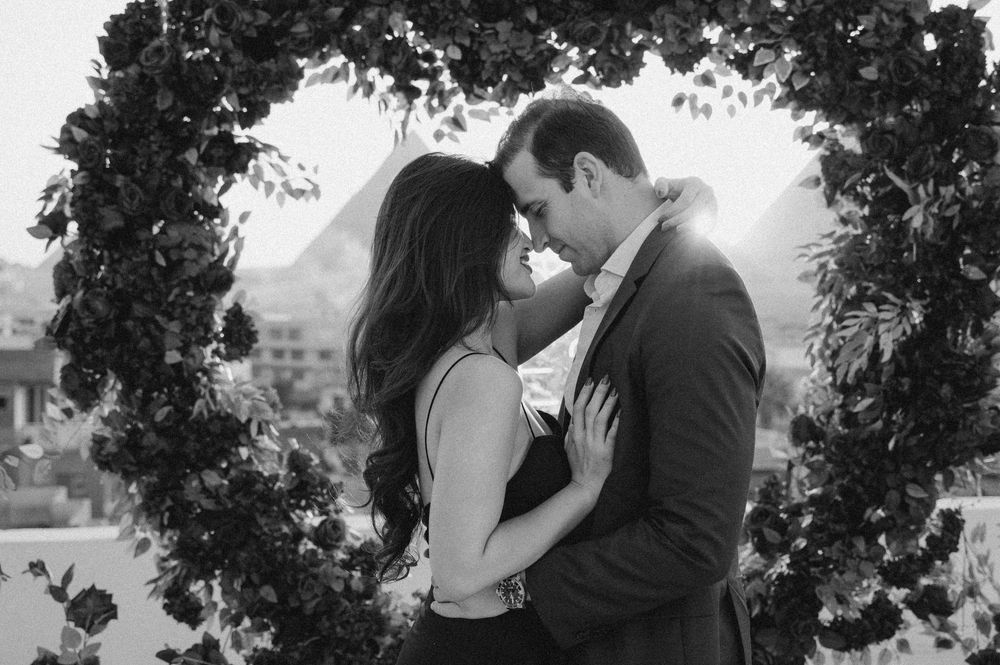 Beautiful couple embracing beneath a sunlit tree canopy in a romantic black and white outdoor photo series.