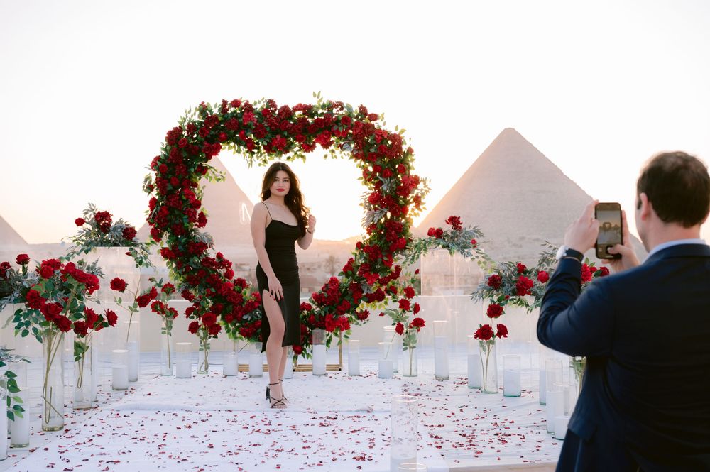 White petals and red floral arrangements decorate an elegant wedding reception ballroom.