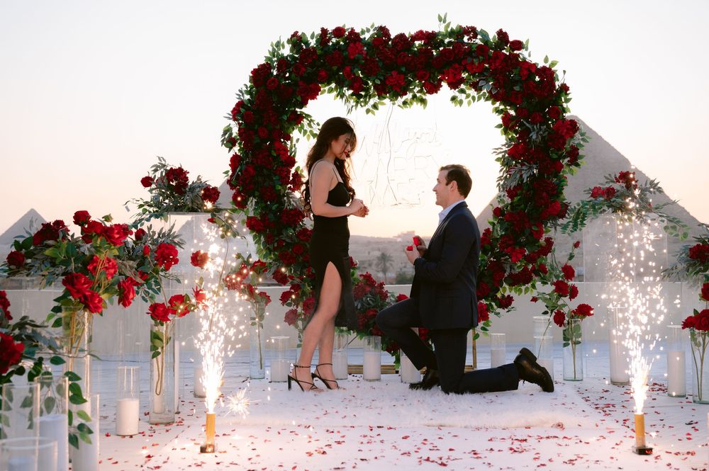 A wedding sequence showing a proposal under a red floral arch with sparklers creating a magical atmosphere.