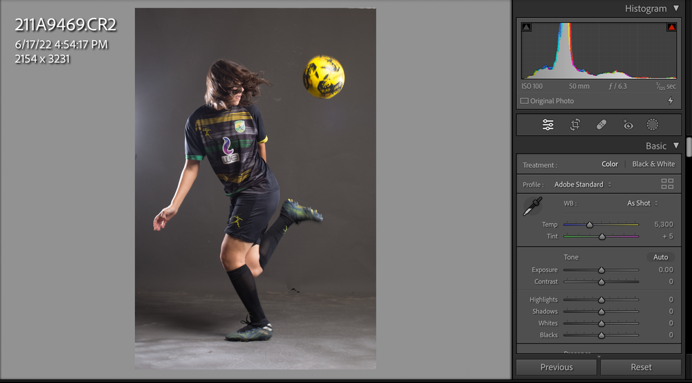 Action shot of an athlete kicking a soccer ball in a studio setting.
