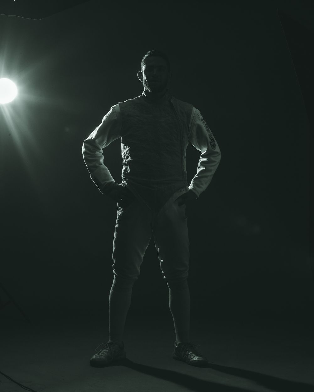 Dramatic silhouette of a figure standing in spotlight against dark background.