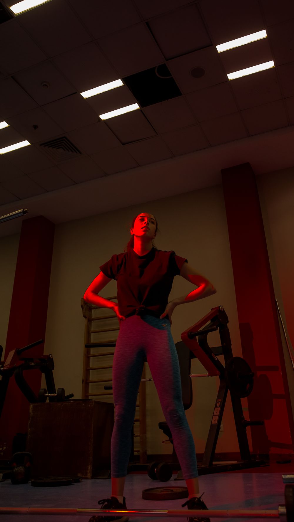 Silhouetted figures exercising in dimly lit red-tinted gym space.