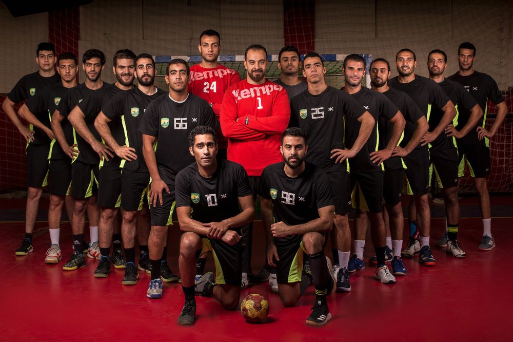 Large group of athletes in black uniforms posing together for team photo - handball team.