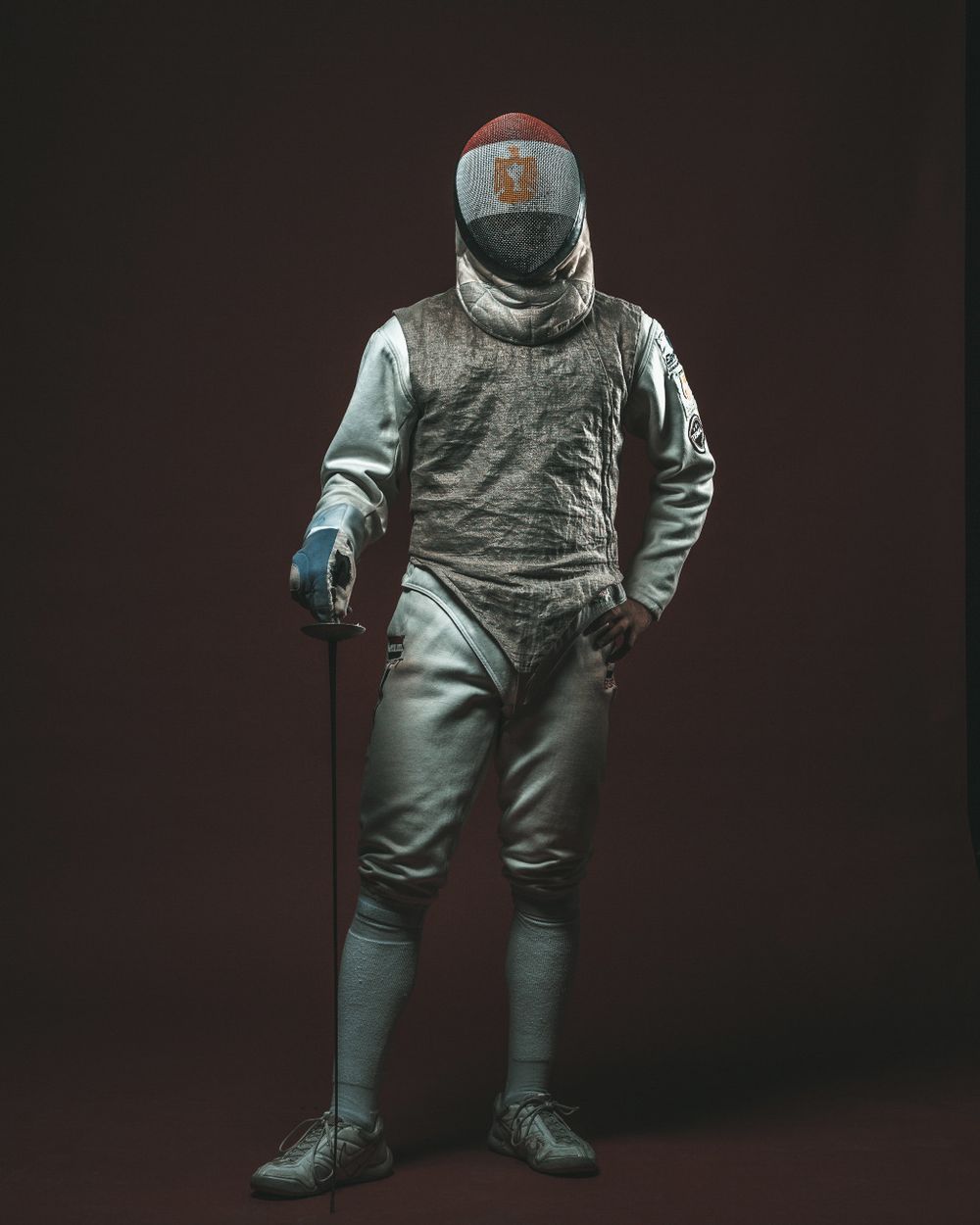 Fencing equipment and protective gear displayed against dark background.