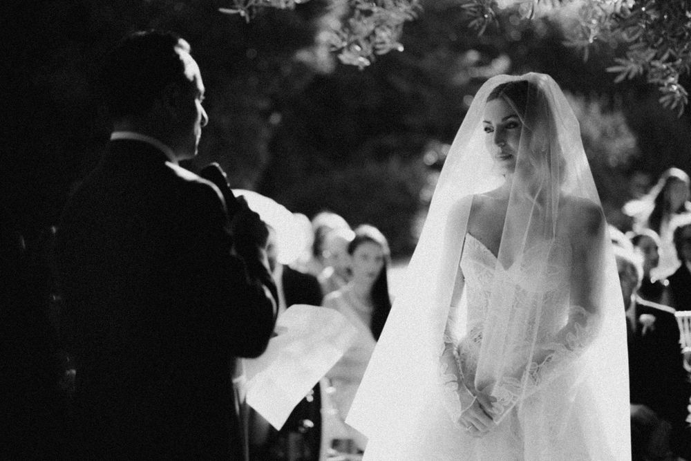 Series of black and white candid ceremony shots showing veiled brides and wedding guests in a garden setting.