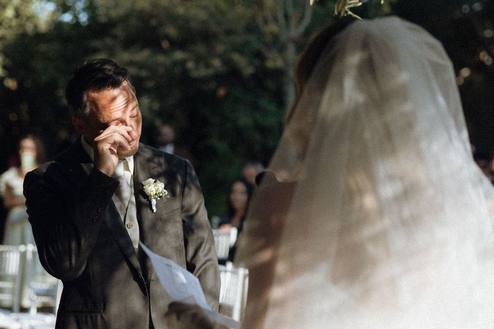 Bride and groom share emotional tender moments during outdoor wedding ceremony.