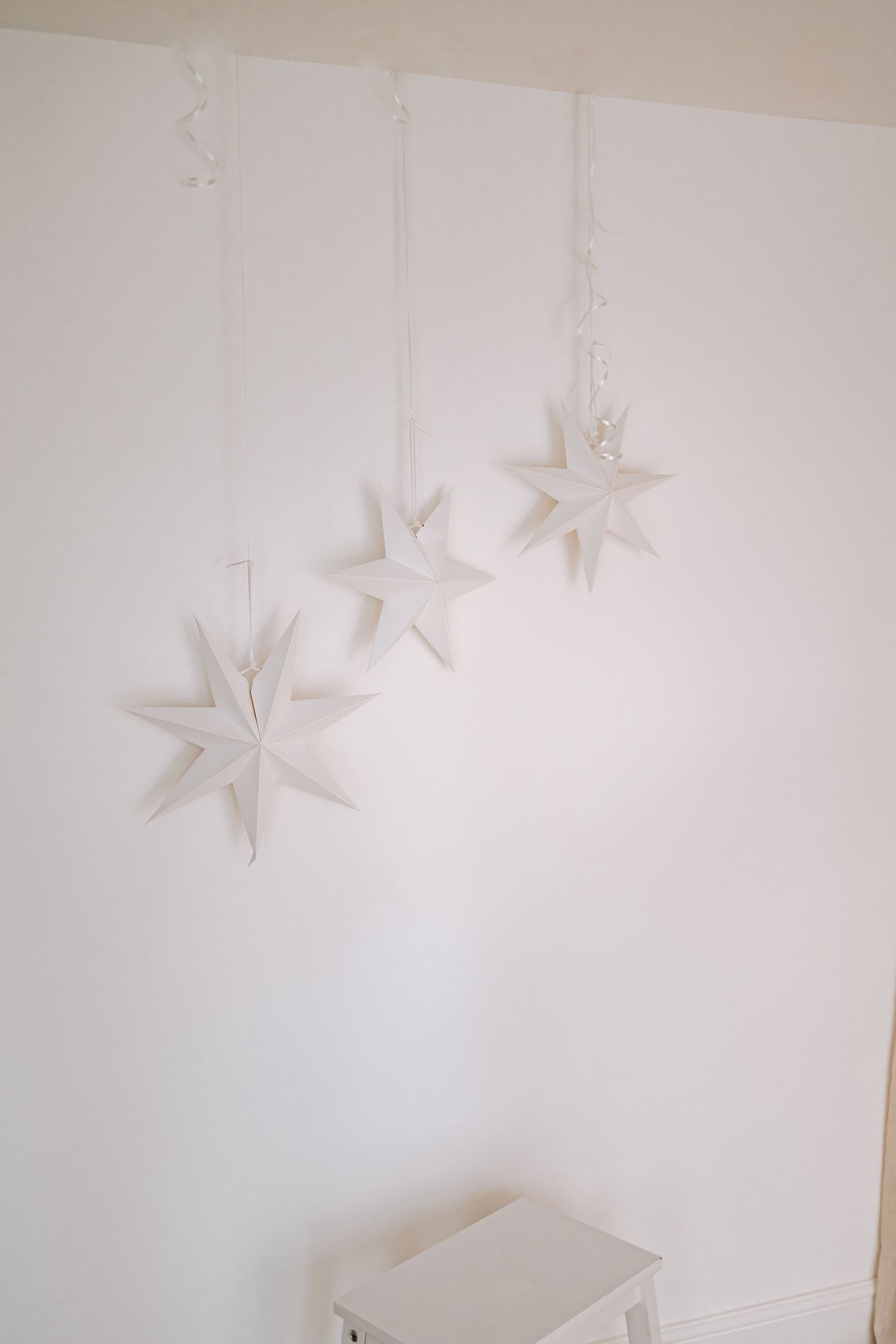 Decor styled images show a Christmas tree and rustic firewood set against white walls in a minimalist holiday scene.