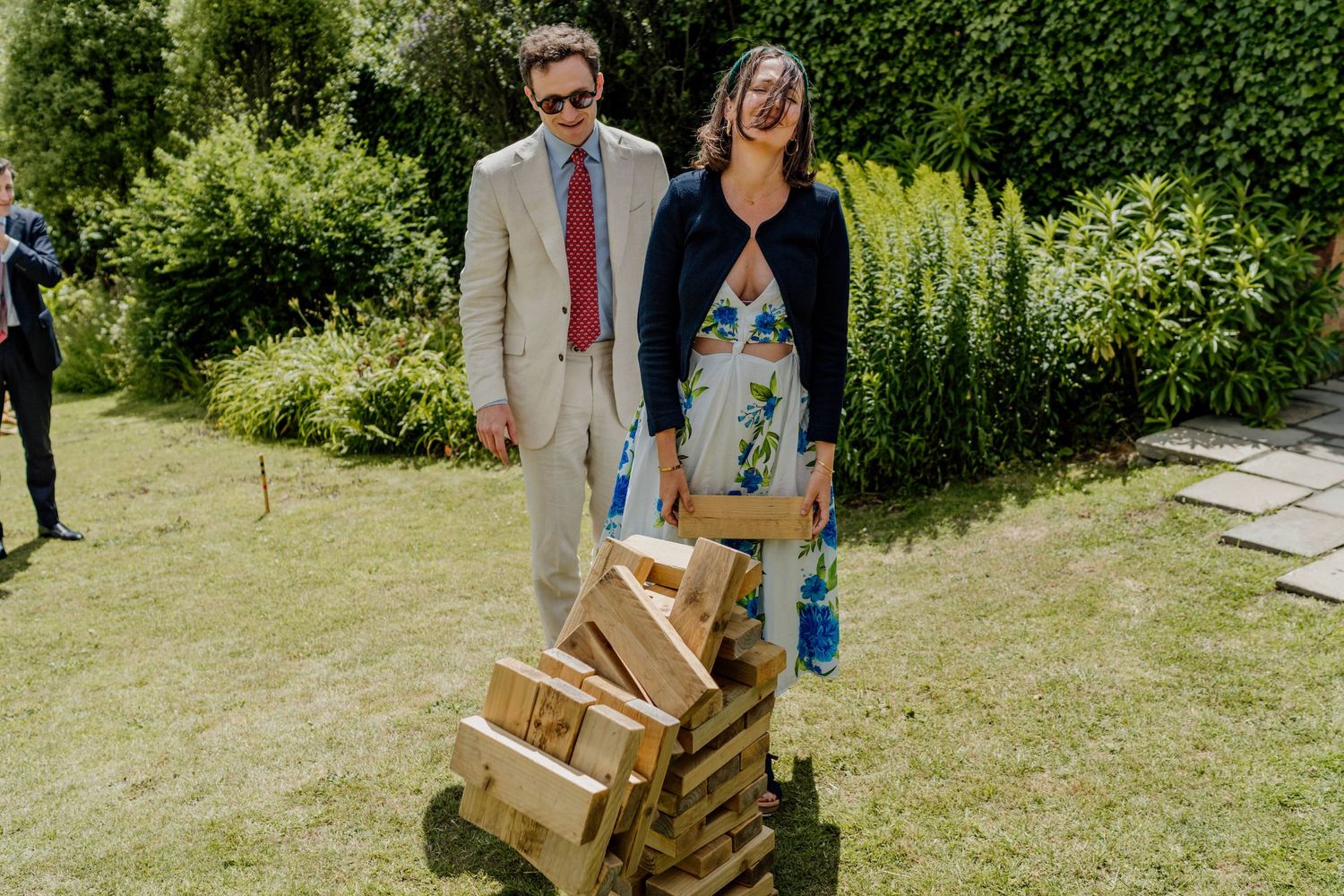Wedding party carrying wooden crates while walking on a grassy outdoor garden path.