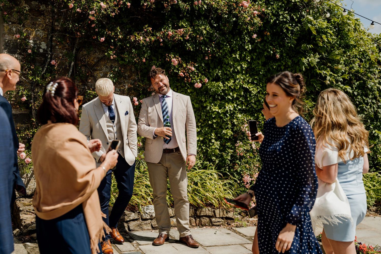 Outdoor wedding reception with twinkle lights and guests mingling in a garden setting.