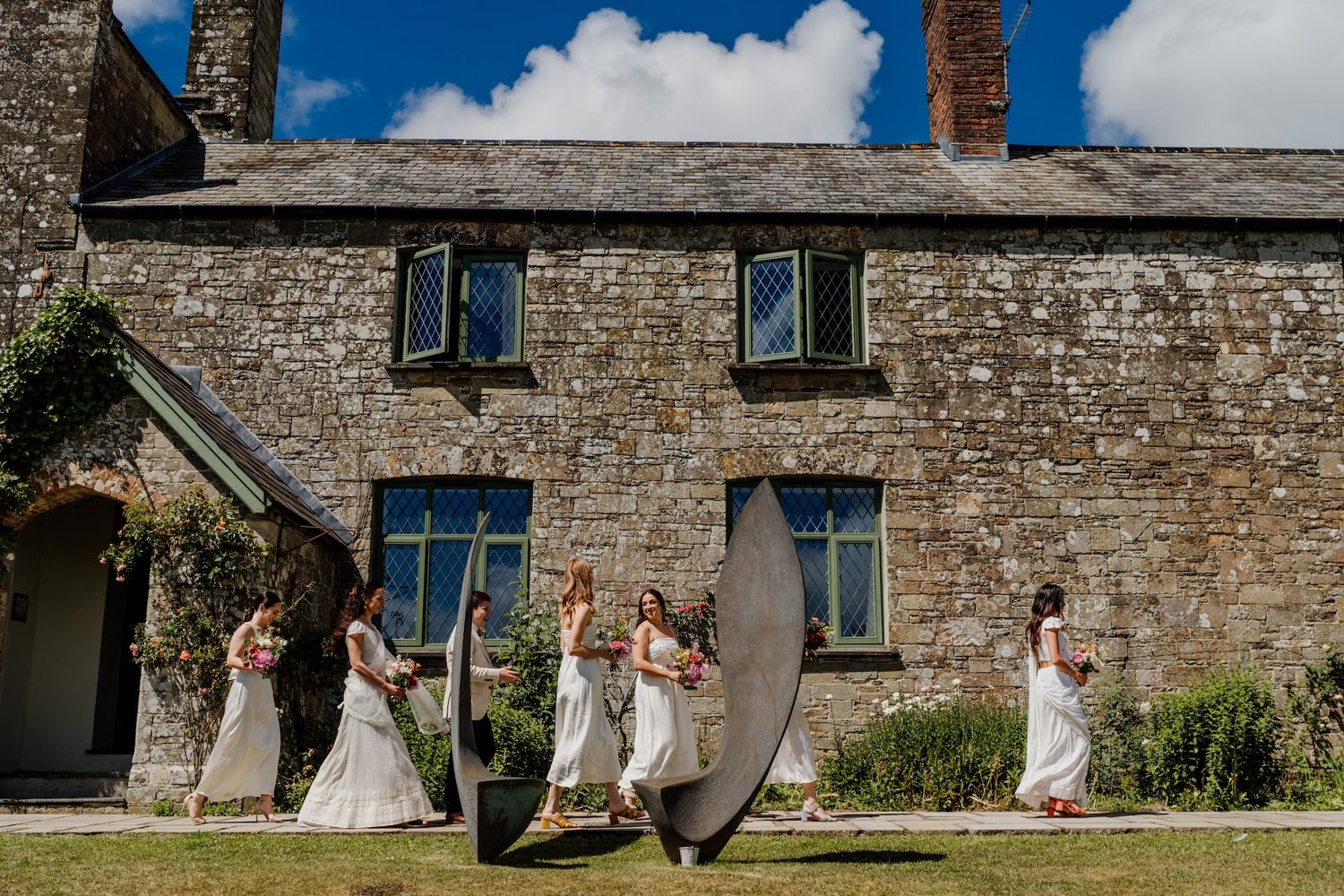 Stone building facade with guests gathered outside on a sunny day.