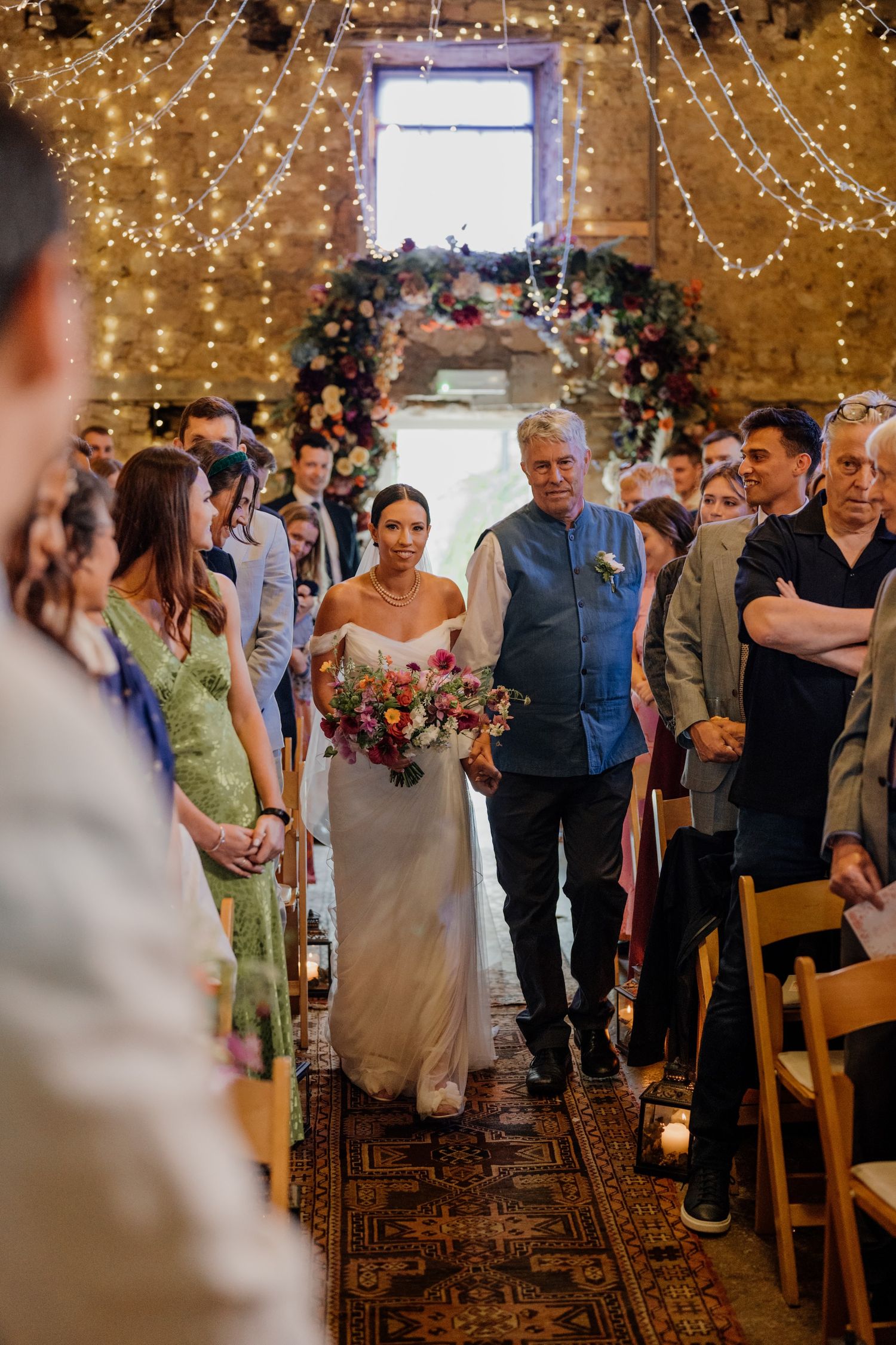 Wedding ceremony in a rustic barn venue decorated with twinkling fairy lights overhead.