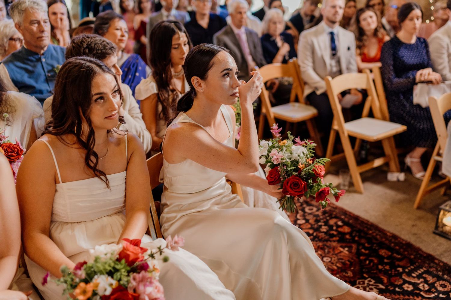 Wedding guests seated in wooden chairs during an indoor ceremony.