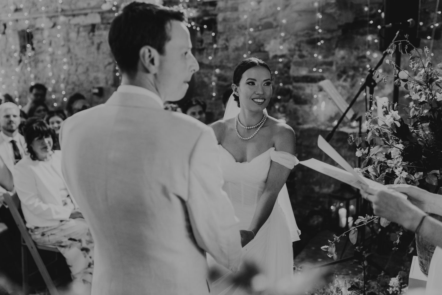 Wedding guests dance and celebrate on an outdoor dance floor decorated with string lights during an evening reception.