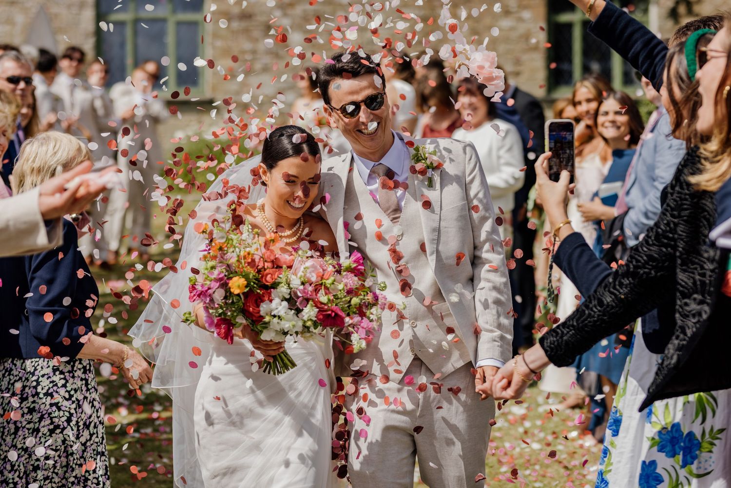 Colorful confetti rains down on dancing wedding guests in a festive celebration atmosphere.