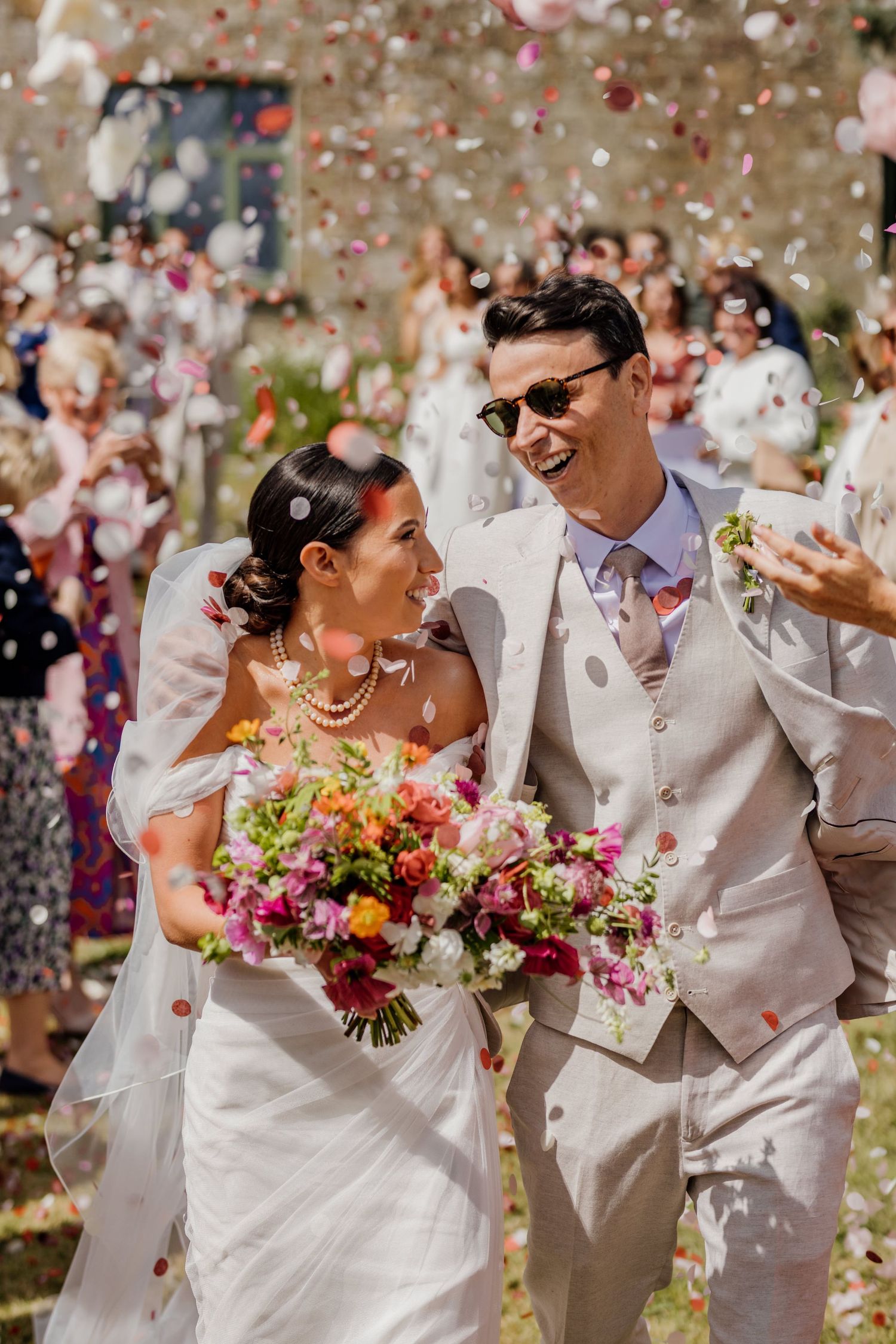 Wedding celebration with colorful flower petals being tossed in joyful outdoor moment.