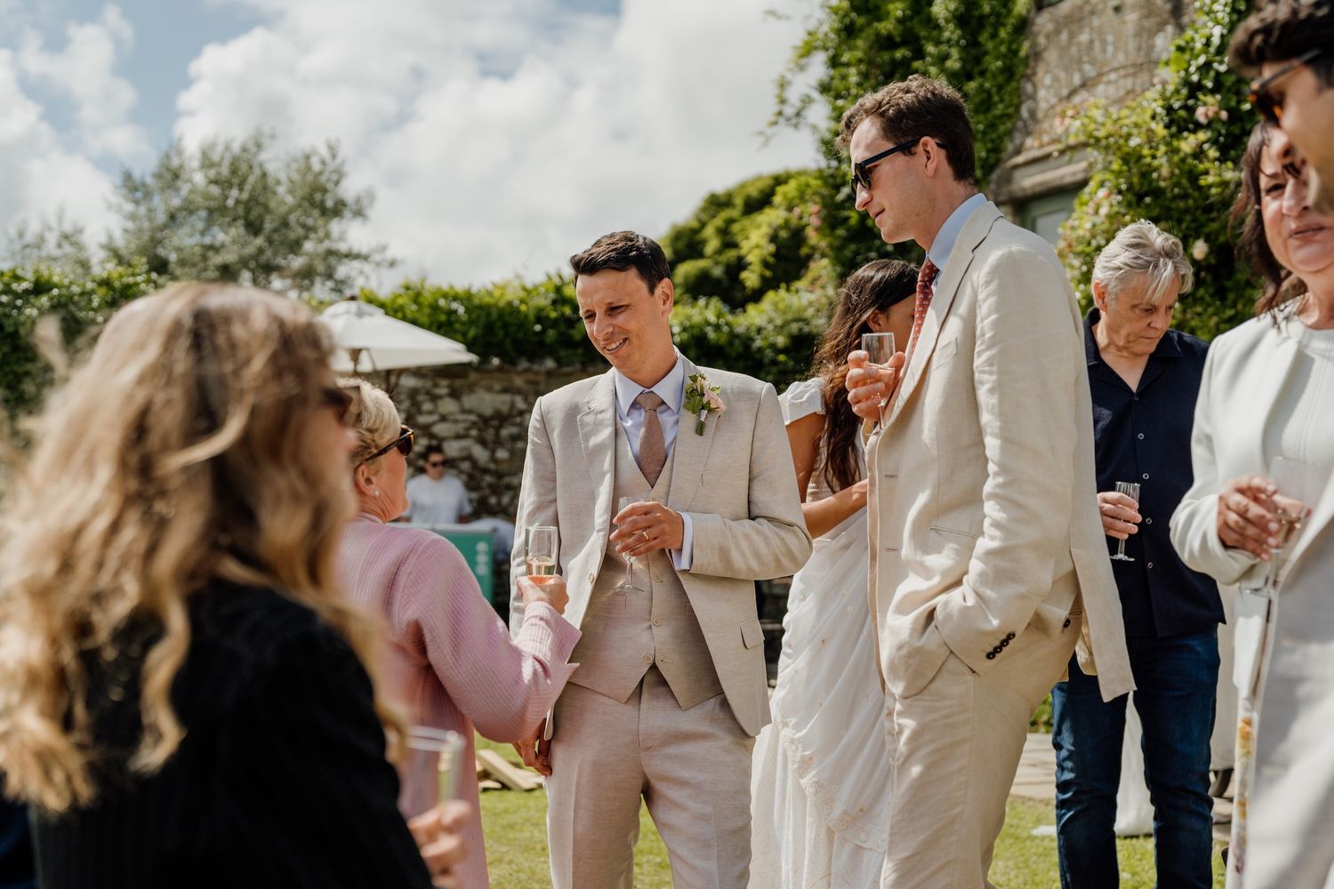Wedding guests enjoying an outdoor celebration against a stone building backdrop.