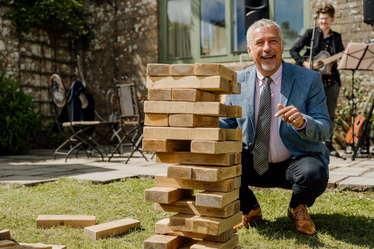 Guests playing giant Jenga game on lawn during outdoor wedding reception.