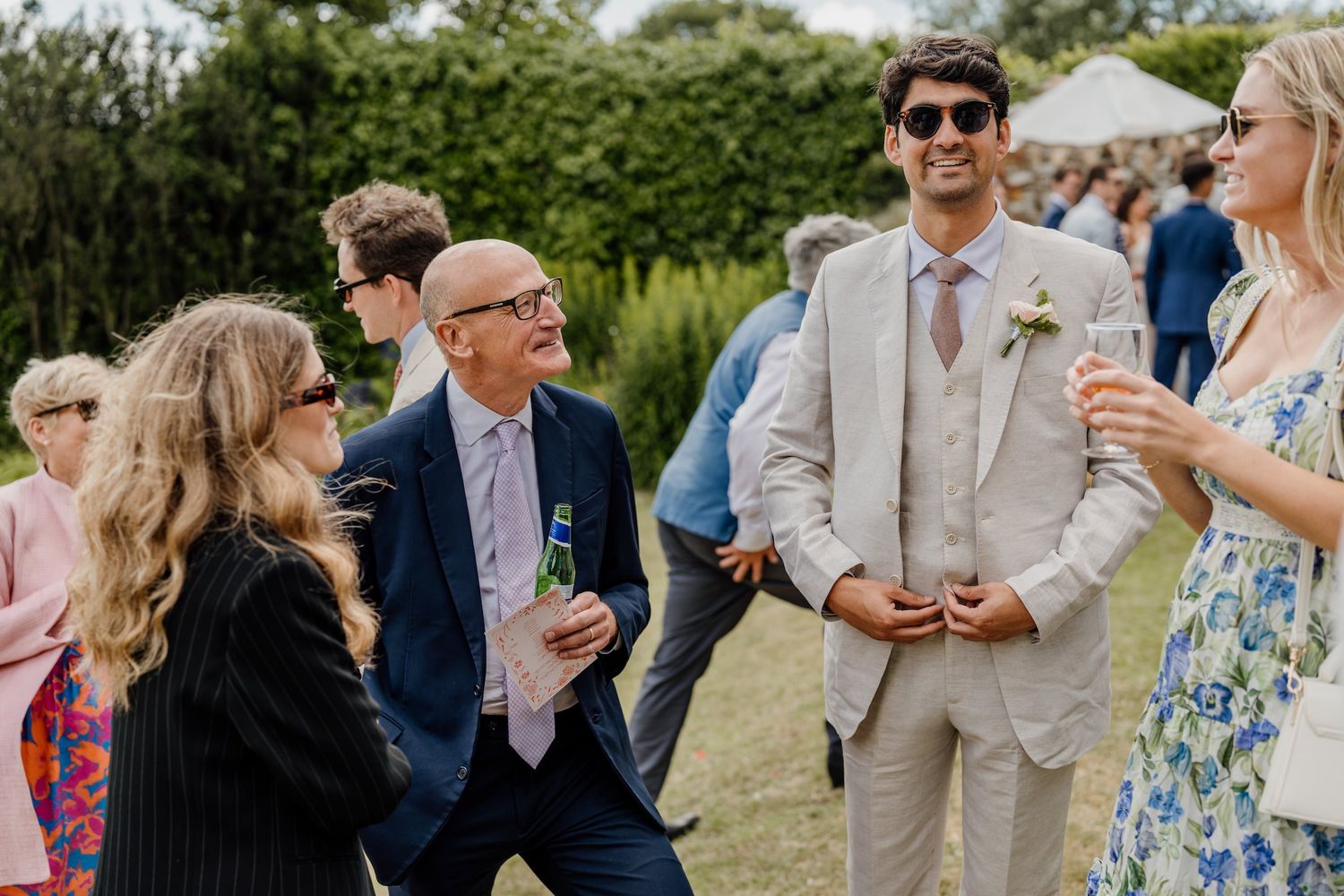 Wedding guests mingle and socialize during an outdoor cocktail hour at an elegant garden reception.