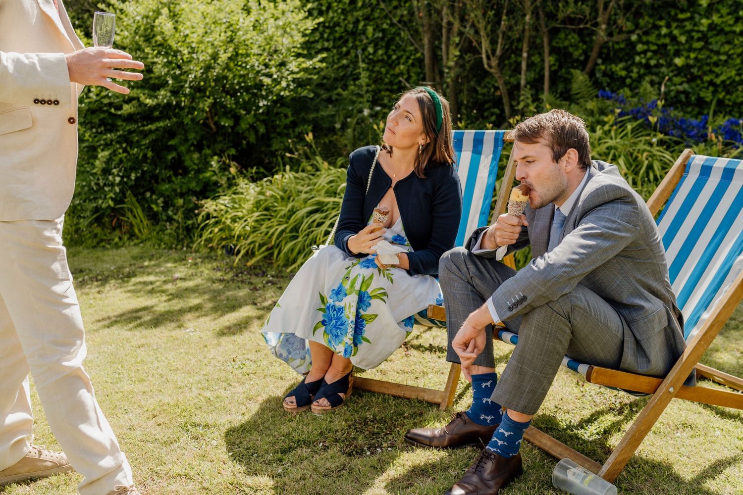 Guests relaxing in striped deck chairs during an outdoor summer garden reception event.