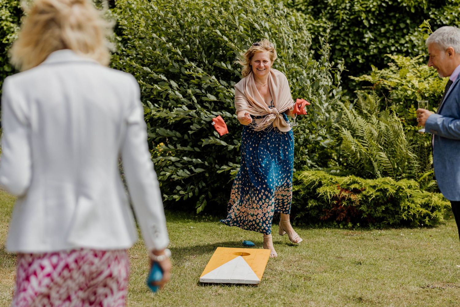 Wedding party plays outdoor lawn games during a fun reception celebration on a sunny day.