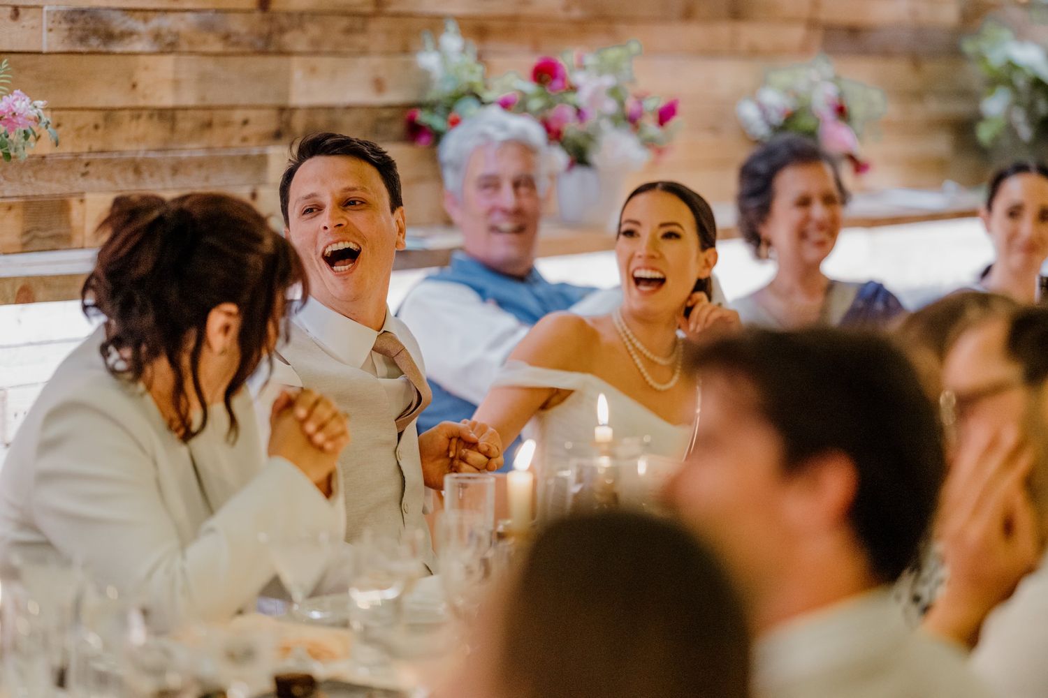 Wedding guests laugh and celebrate together at a rustic barn reception venue.