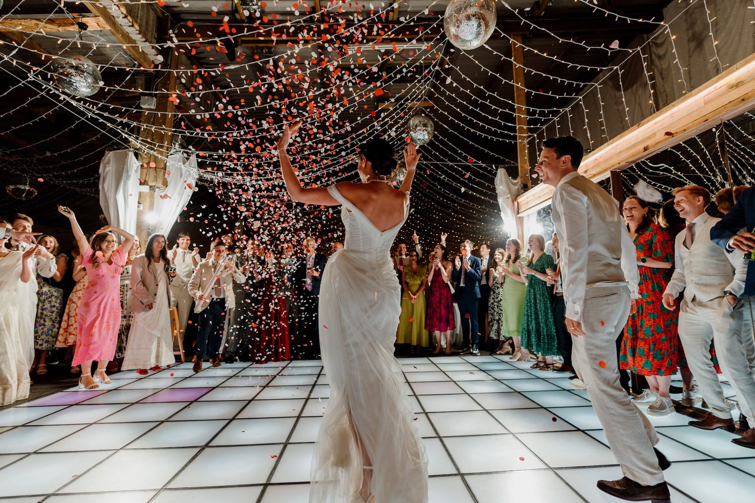 Wedding reception guests dancing under a canopy of twinkling string lights and copper accents.