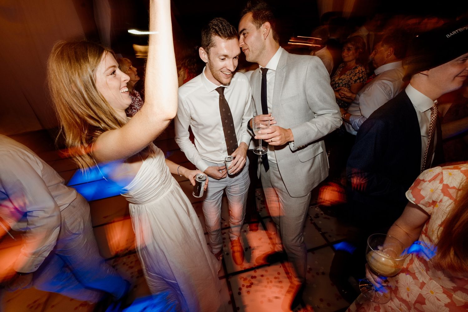 Guests dancing and enjoying themselves at a lively wedding reception with blue lighting effects.