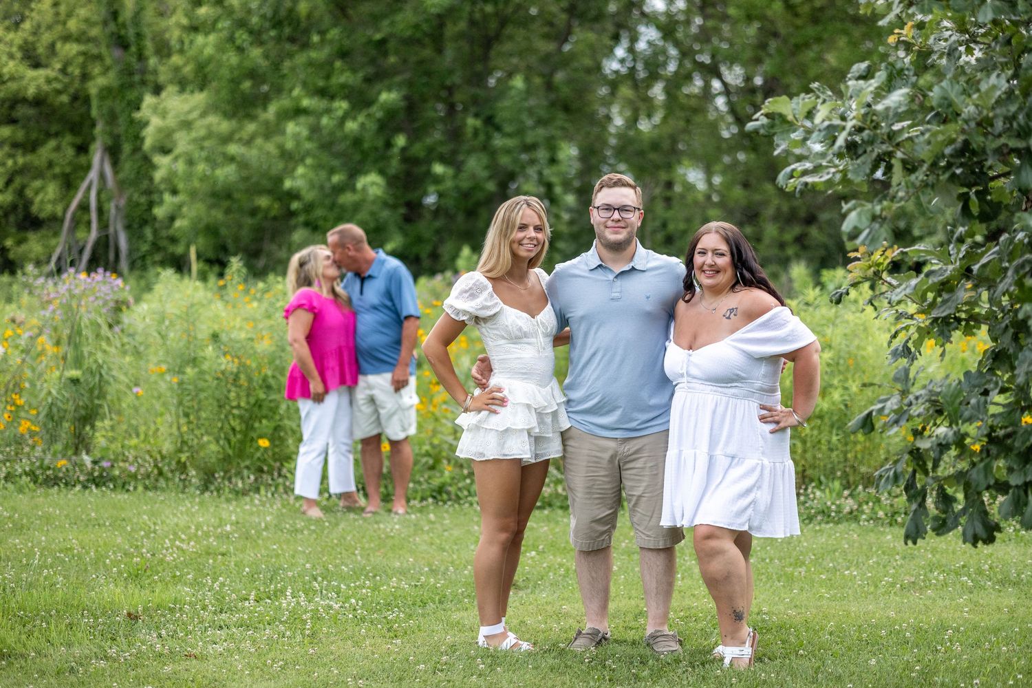 Springfield, IL photographer captures siblings in the foreground with parents in the back during a session in Centennial Park in Central IL