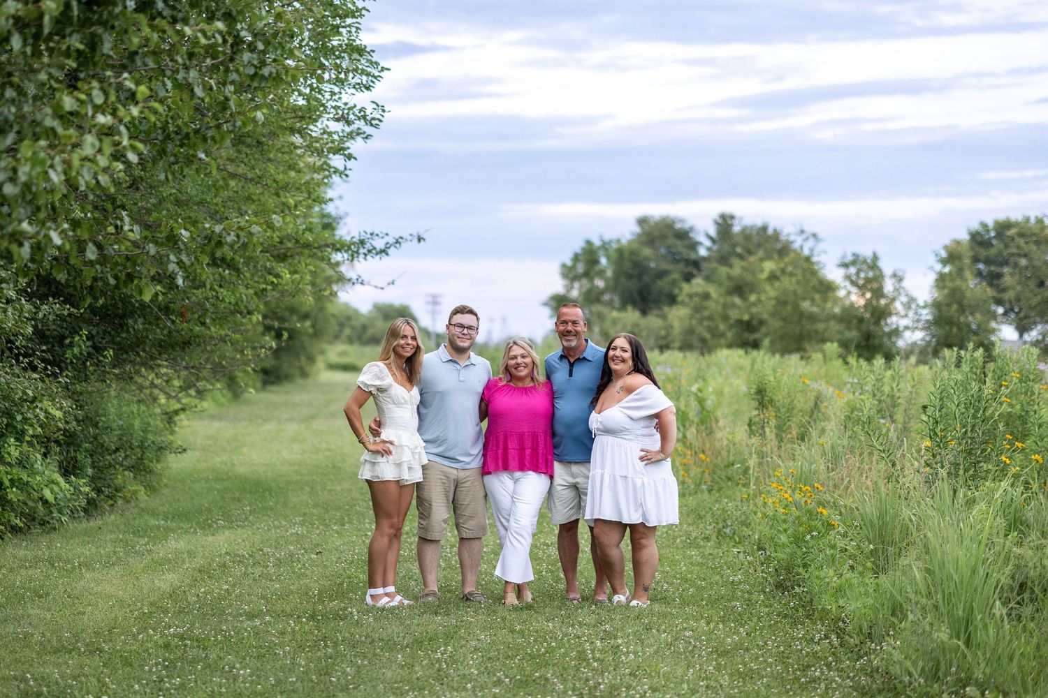 Springfield, IL photographer captures a family together in a clearing near wildflowers at Centennial Park in Central Il