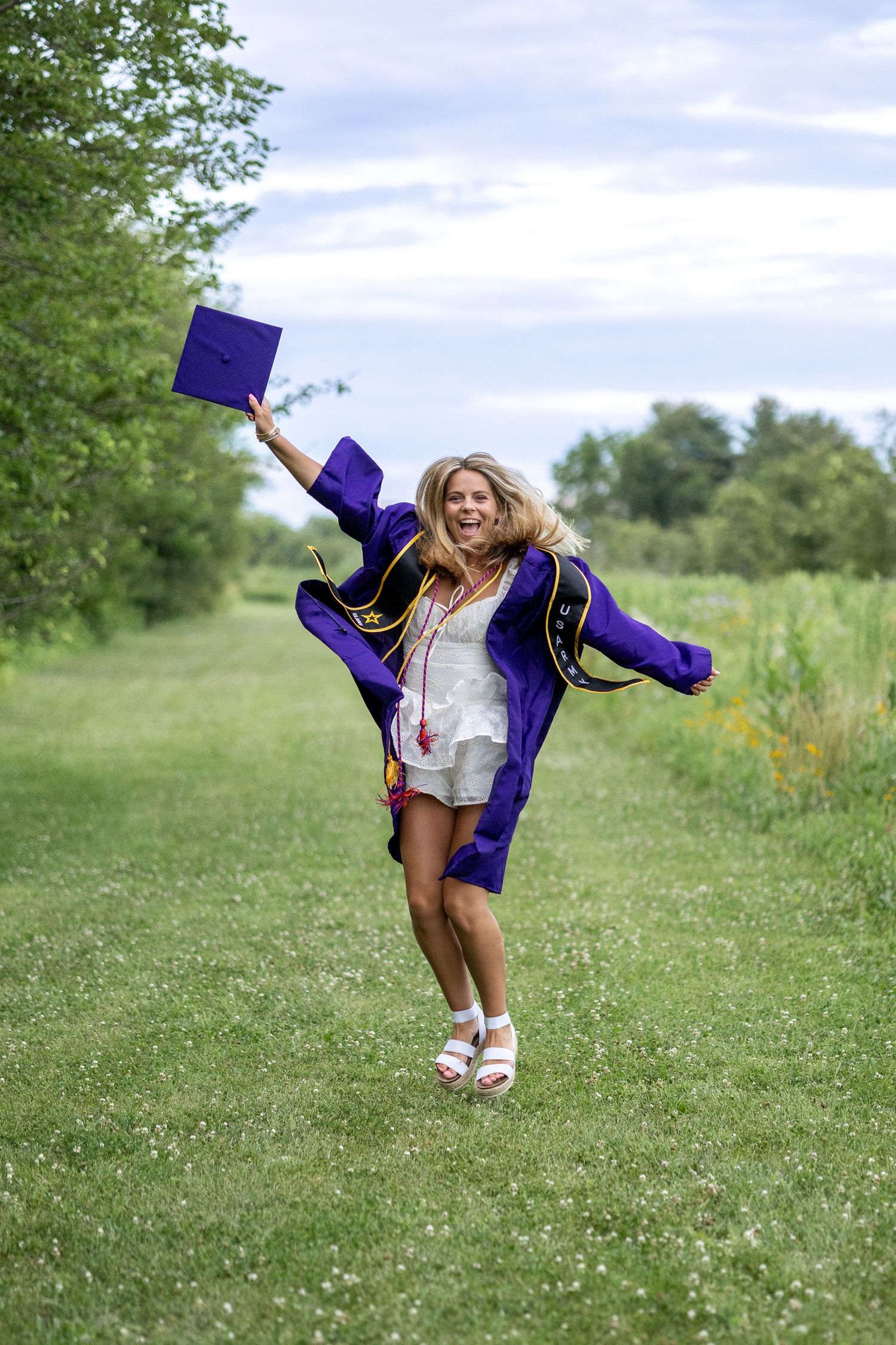 Springfield, IL photographer captures a graduated senior jumping with a cap and gown during a photo session at Centennial Park in Central IL