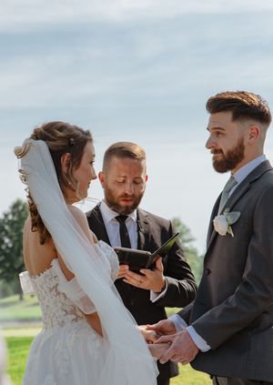 Intimate wedding ceremony moments exchanging rings on a sunny outdoor terrace.