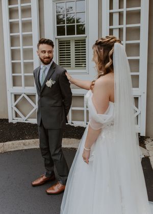 First look moment captured in front of white columns and windows at an elegant venue.