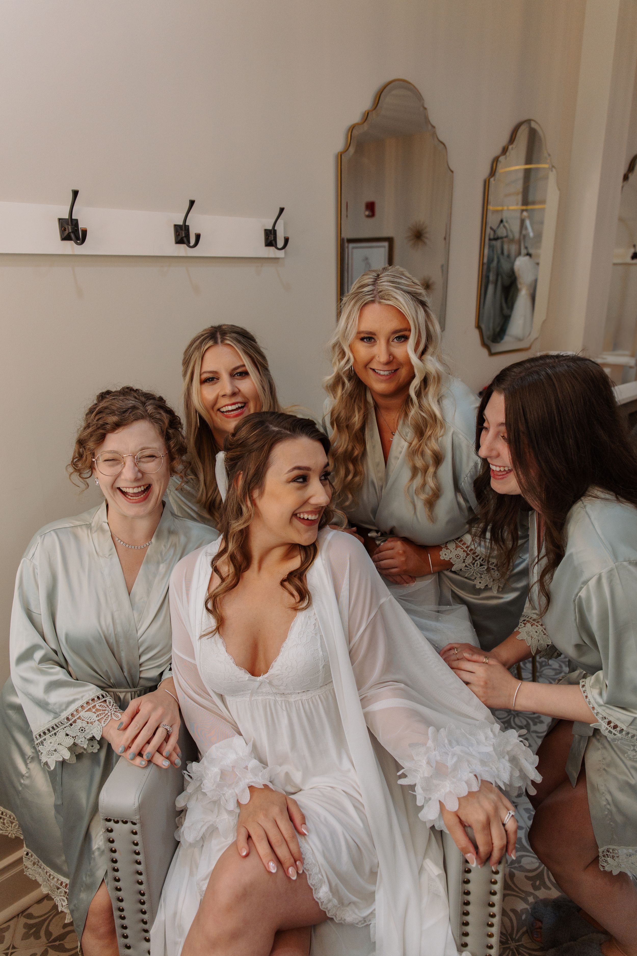 Bridesmaids in matching light blue robes share laughter and joy while getting ready for a wedding celebration.